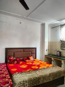 a bedroom with a bed with a red comforter at Shri Ram seva sadan in Vrindāvan