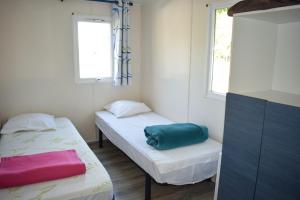 two beds in a small room with two windows at Camping du Creulet in Crouay