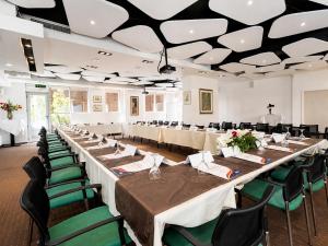 a large banquet hall with tables and green chairs at Hotel Nartel in Prishtinë