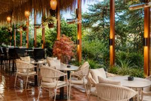 a restaurant with tables and chairs and trees at Hotel Nartel in Prishtinë