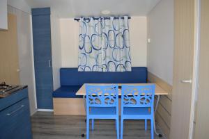 a kitchen with a table and two blue chairs at Camping du Creulet in Crouay