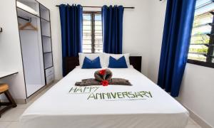 a teddy bear laying on a bed with a happy anniversary sign at Roche Kerlan Apartments in Anse Kerlan