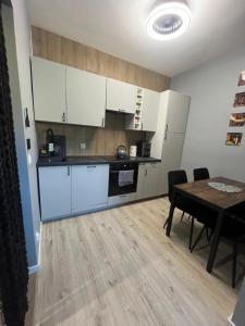 a kitchen with white cabinets and a table with chairs at Apartament nad rzeką in Głuszyca