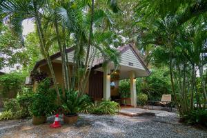 a small house with palm trees in front of it at Baan Suan ChiChan บ้านสวนชีจรรย์ in Na Jomtien