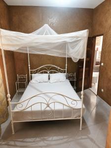 a white bed with a canopy in a room at Résidence Les Bernier in Nianing +26 photos