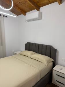 a bed with a gray headboard in a bedroom at Velipoja Guest House 1 in Velipojë