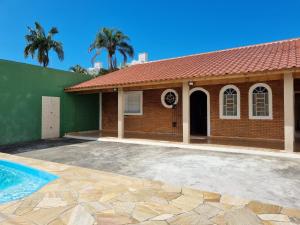 a house with a swimming pool in front of it at Acolhedora casa renovada - Piscina e a 100m da praia in Caraguatatuba