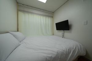 a bedroom with two beds and a flat screen tv at Goseong Sustay Pension in Goseong