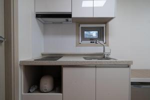 a kitchen with white cabinets and a sink at Goseong Sustay Pension in Goseong
