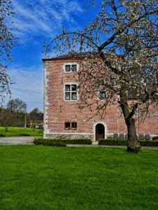 a brick building with a tree in front of it at La tour de la Chapelle in Couthuin