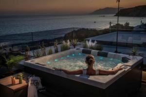 a person in a jacuzzi tub with the ocean at Lapis Nera Villas - Beachfront & "Free" Heated Pools in Psari Forada