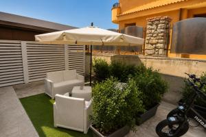a patio with an umbrella and chairs and plants at Tirone Luxury Rooms in Cirò Marina