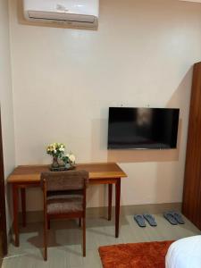 a room with a desk with a television and a table with a chair at Armatyr Motel in Kampala