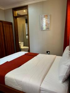 a bedroom with a large white bed and a bathroom at Armatyr Motel in Kampala +3 photos
