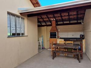 a patio with a picnic table and a grill at Acolhedora casa renovada - Piscina e a 100m da praia in Caraguatatuba