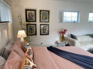 a bedroom with a bed and pictures on the wall at Wattle Downs Palm Beach Studio in Auckland