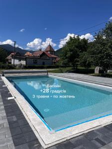 a swimming pool in front of a house at Karpatske Vidlunnya in Mykulychyn