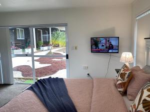 a living room with a couch and a tv on the wall at Wattle Downs Palm Beach Studio in Auckland