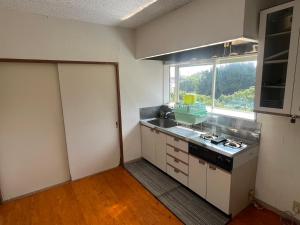 an empty kitchen with a stove and a window at 海岸道路沿い 磯の宿 in Minamiboso