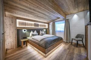a bedroom with a large bed and a chair at Dosplain Panoramic Apartments in Santa Cristina Gherdëina