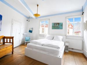 a white bedroom with a bed and a chair at Stilhaus 1730 in Königsbach Stein