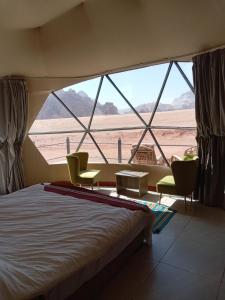 a bedroom with a large window with two chairs and a bed at Wadi Rum Panorama Suites in Disah