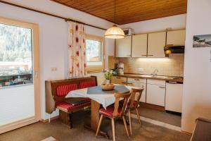 a kitchen with a table and chairs and a kitchen with a window at Almblick Appartements in Sankt Jakob in Defereggen