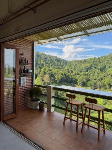 a balcony with two chairs and a view of the mountains at หมี่ก่าโฮมสเตย์ in Ban Pha Mi