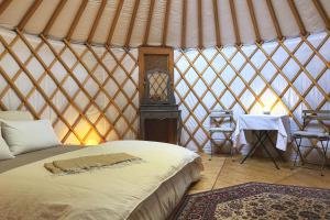 a room with a bed and a table in a yurt at Yourte pour deux - Voie Bleue in Bayon