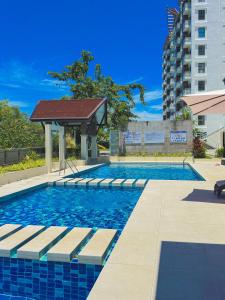 a swimming pool with a gazebo next to a building at Azure Edge in Dauis