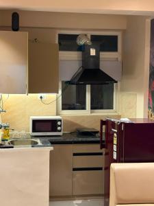 a kitchen with a microwave and a stove top oven at Bright & Modern 1BHK in Ghaziabad