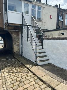 a house with stairs next to a body of water at Cosy Flat - Over Arch in Oswaldtwistle