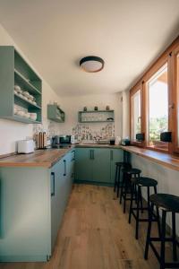 a kitchen with green cabinets and a counter with stools at Három Sziget Vendégház in Dunasziget