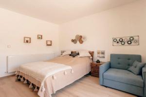 a bedroom with a bed and a blue chair at Három Sziget Vendégház in Dunasziget