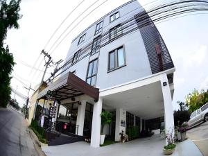 a large white building with windows on a street at Debua Mahasarakham in Maha Sarakham