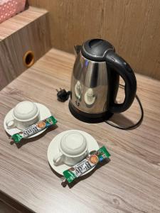 a tea kettle on a wooden table with two plates at Nava Grand in Ban Talat Rangsit