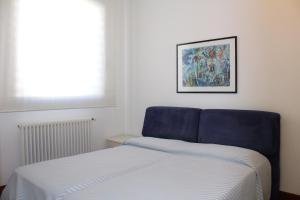 a bed in a bedroom with a blue chair next to a window at Residenza Nervesa in Lignano Sabbiadoro