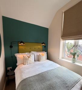 a bedroom with a large bed with a green wall at The Stokesay Boutique Townhouse Ludlow in Ludlow