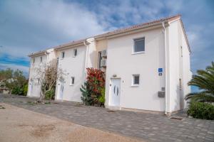 a white building with a garage at Beachfront Reiterer Villa V2 with Seaview 30 meters from the Beach - CROWONDER LUXURY RENT in Privlaka
