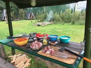 a picnic table with meat and vegetables on it at Vigio Brasta camping in Elektrėnai