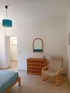 a bedroom with a chair and a dresser and a mirror at Casa Marina mare e relax in Marina Palmense