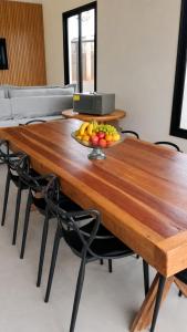 a wooden table with a bowl of fruit on it at Recanto Três Rios in Santa Clara dʼOeste +5 photos