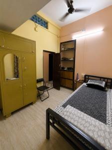 a bedroom with two beds and a cabinet and a chair at Jagdamba Bhawan in Kolkata