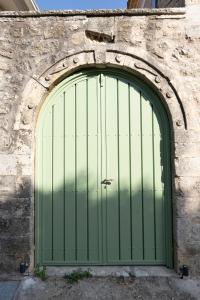 a green garage door in a stone wall at Dervisia Stonehouse 2 in Lazaráta