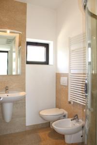 a bathroom with a sink and a toilet and a mirror at Residenza Nervesa in Lignano Sabbiadoro +22 photos
