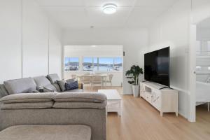 a living room with a couch and a flat screen tv at Central Coast Waterfront 2BR with Jetty Access in Koolewong