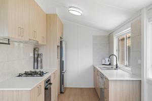 a kitchen with white counters and a sink and a stove at Central Coast Waterfront 2BR with Jetty Access in Koolewong +14 photos
