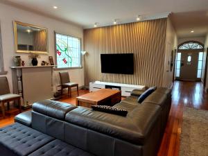 a living room with a leather couch and a flat screen tv at Westend House Healesville in Healesville