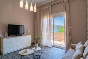 a living room with a tv and a large window at Studios Diogenis in Porto Koufo