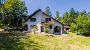 a small white house with a grass yard at Gorska Vila Sisevac in Sisevac